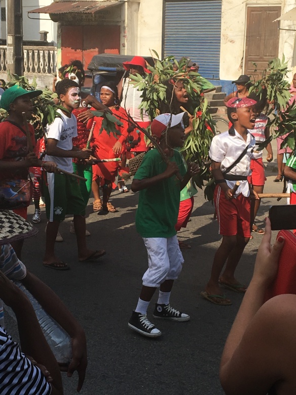 Students, dressed in festive colors and litchi branches, sing during a street parade in Tamatave